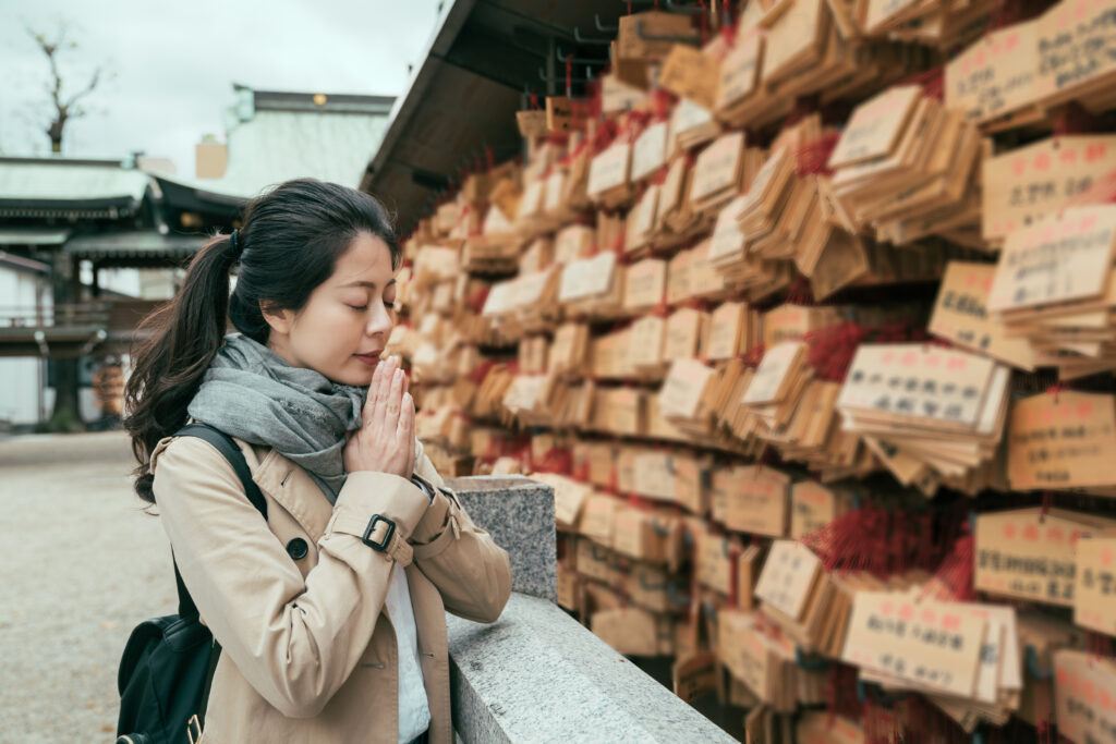 A woman offering an ema (votive tablet) and praying.