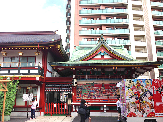 People taking pictures of a truck with anime "Love Live!" painted on it parked in the precincts of Kanda Myojin.